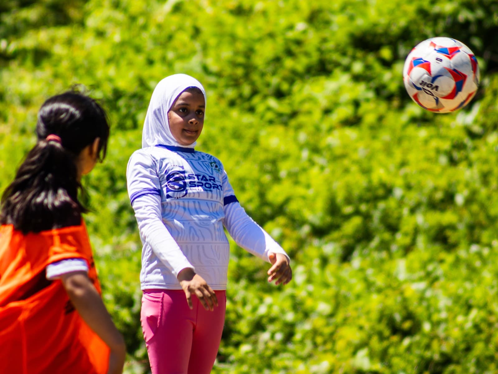 A girl in a Star Sports jersey watches the ball come down