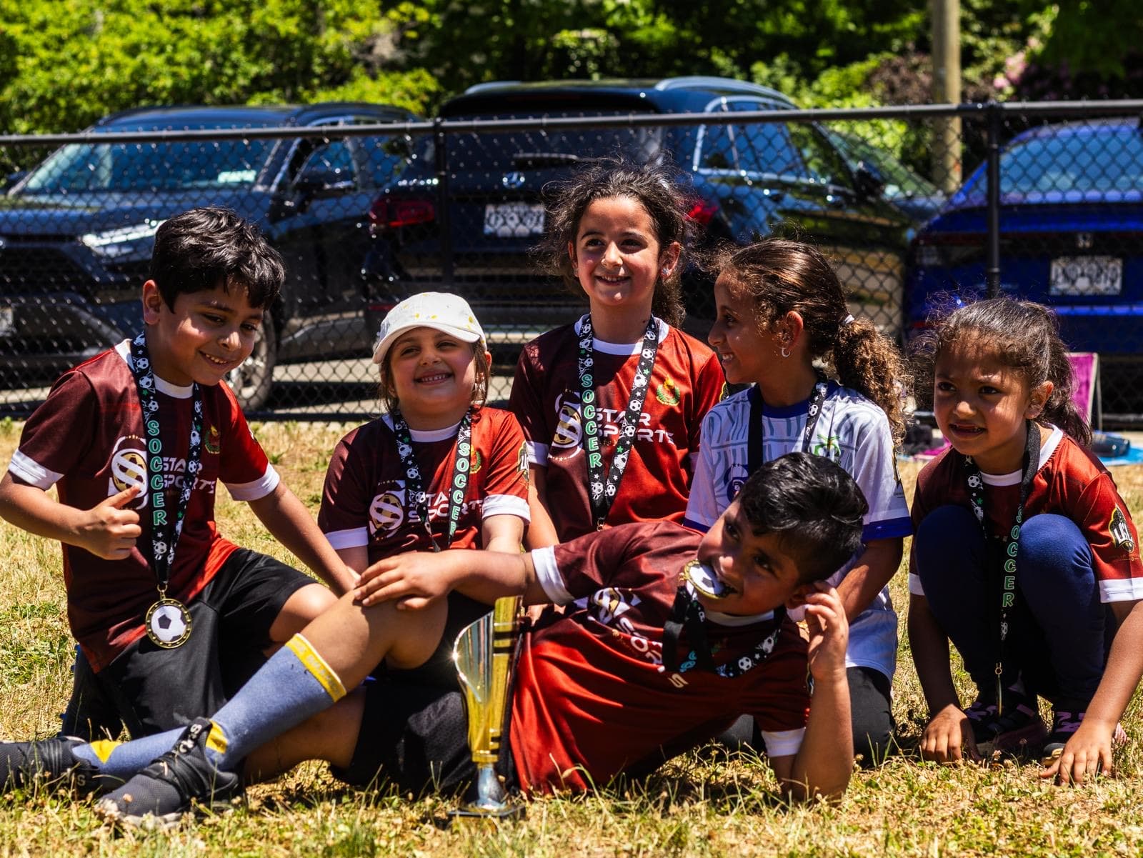 Young players in red kits with their medals and a trophy after a tournament